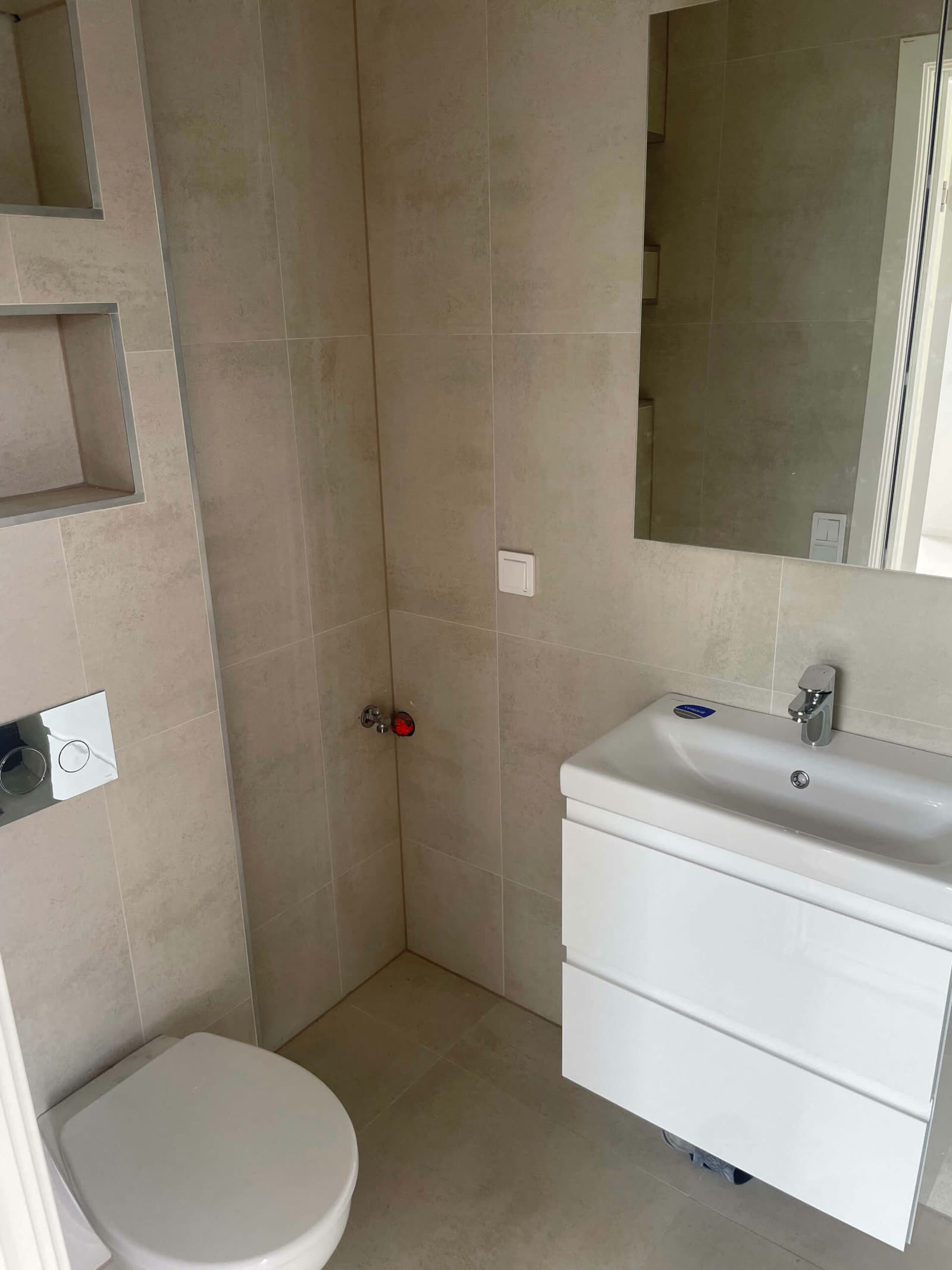 Łazienka z WC, umywalką i wnęką ścienną wyłożoną płytkami